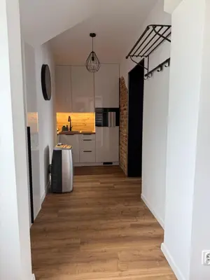 a kitchen with white cabinets and a hardwood floor at Apartament Grojec in Grojec