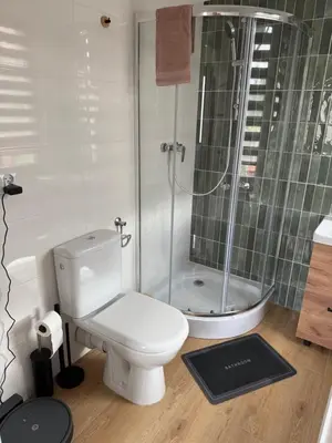 a bathroom with a white toilet and a shower at Apartament Grojec in Grojec