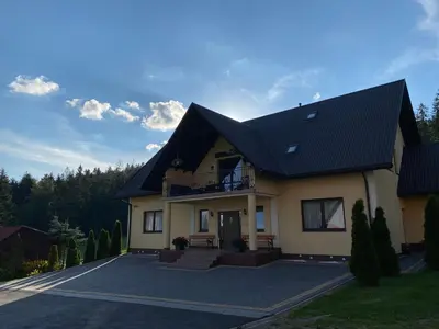a large house with a black roof at Noclegi Pod Lasem in Zubrzyca Górna