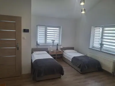 a room with two beds and a table and windows at Mieszkanie Paszkówka in Paszkówka