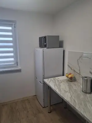 a kitchen with a refrigerator and a table with fruit on it at Mieszkanie Paszkówka in Paszkówka