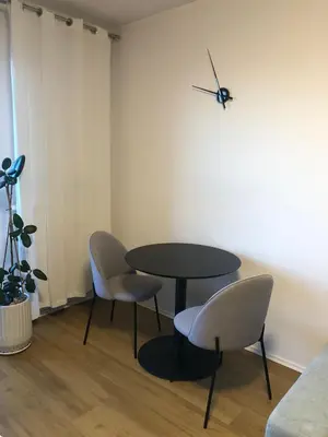 a table and two chairs and a clock on a wall at Komfortowy apartament blisko Tauron Areny in Kraków