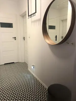 a bathroom with a round mirror and a tile floor at Komfortowy apartament blisko Tauron Areny in Kraków