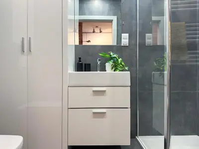 a white bathroom with a sink and a shower at Apartament Śliwka w Krakowie in Kraków