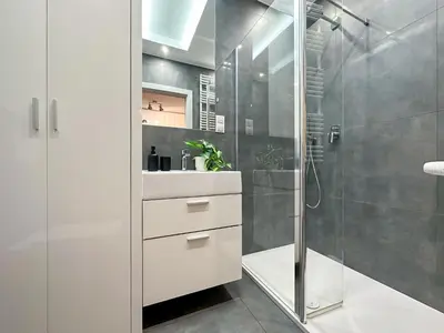 a white bathroom with a shower and a sink at Apartament Śliwka w Krakowie in Kraków
