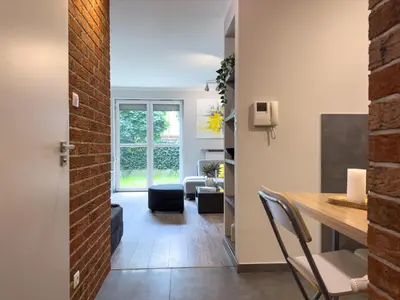 a living room with a table and chairs and a brick wall at Apartament Śliwka w Krakowie in Kraków