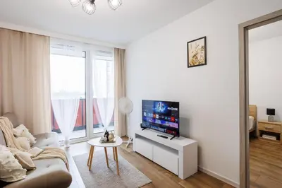 a white living room with a couch and a tv at Malila Premium Apartments Łaszkiewicza 8 -Tauron Arena Parking in Kraków