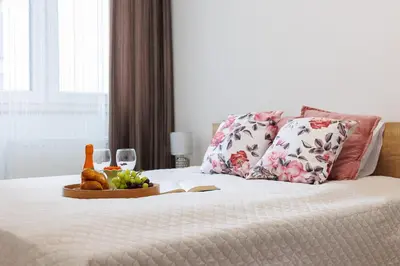 a bed with a tray of fruit and wine glasses at Malila Premium Apartments Łaszkiewicza 8 -Tauron Arena Parking in Kraków