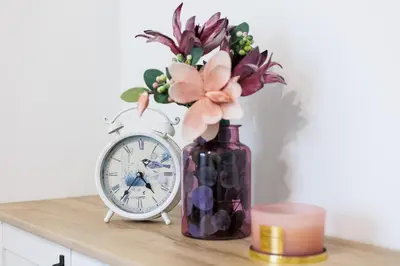 a vase of flowers and a clock on a table at Malila Premium Apartments Łaszkiewicza 8 -Tauron Arena Parking in Kraków