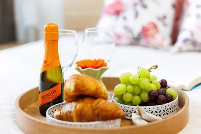 a tray of food with a bottle of wine and grapes at Malila Premium Apartments Łaszkiewicza 8 -Tauron Arena Parking in Kraków