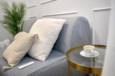 a coffee cup on a glass table next to a couch at MIYABI Apartment in Kraków