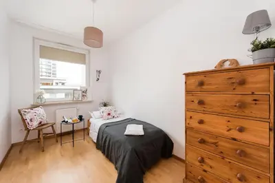 a bedroom with a bed and a wooden dresser at Jasmine's apartment in Kraków