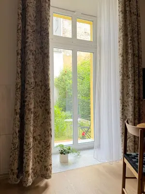 a window with curtains and a plant in front of it at Szlak Loft in Kraków