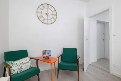 two chairs and a table in a room with a clock at Bright Two-Bedroom Apartment in Nowa Huta by Noclegi Renters in Kraków