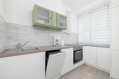 a kitchen with white cabinets and a sink at Bright Two-Bedroom Apartment in Nowa Huta by Noclegi Renters in Kraków