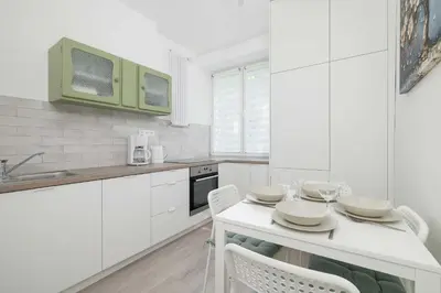 a kitchen with white cabinets and a white table and chairs at Bright Two-Bedroom Apartment in Nowa Huta by Noclegi Renters in Kraków