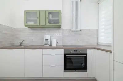 a kitchen with white cabinets and a sink and an oven at Bright Two-Bedroom Apartment in Nowa Huta by Noclegi Renters in Kraków