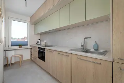a kitchen with wooden cabinets and a sink and a window at Family Apartment with Air Conditioning with 3 Bedrooms in Cracow by Noclegi Renters in Kraków