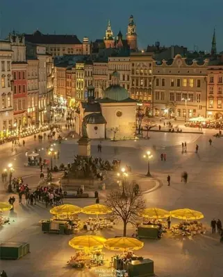a city square with tables and yellow umbrellas at night at Ekskluzywny apartament, Browar Lubicz, FREE Parking in Kraków