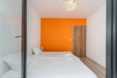 a bedroom with two beds and an orange wall at Riverside Comfort Apartment by BookingHost in Kraków
