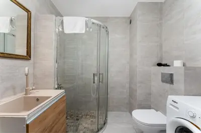 a bathroom with a shower and a toilet and a sink at Riverside Comfort Apartment by BookingHost in Kraków