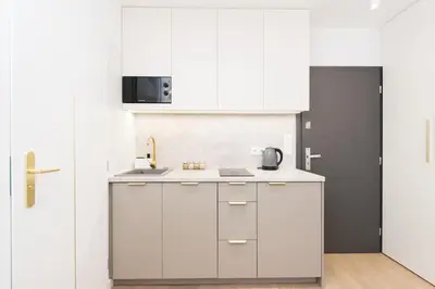 a kitchen with white cabinets and a sink at Cozy Flat with a Garden in Kraków