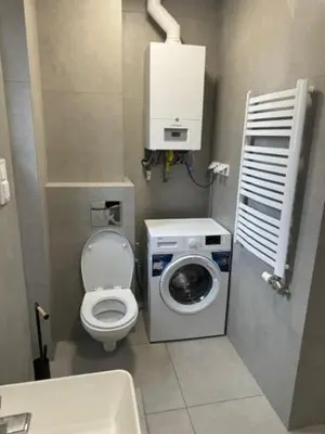 a small bathroom with a toilet and a washing machine at Apartament ,nocleg, wysoki standard in Niepołomice
