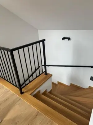 a staircase with a black railing and wooden floors at Apartament ,nocleg, wysoki standard in Niepołomice