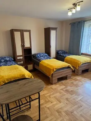 a room with three beds with yellow covers and a wooden floor at Bochnia,kwatery pracownicze,duży dom, noclegi in Bochnia