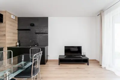 a hallway with white walls and wooden doors at Zabłocie Deluxe Apartment by BookingHost in Kraków