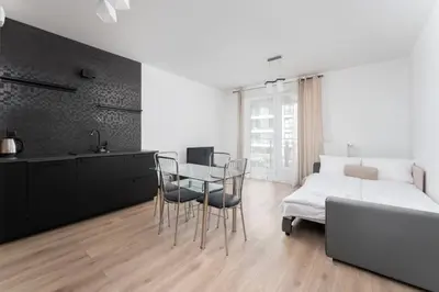 a white bedroom with a large bed and a tv at Zabłocie Deluxe Apartment by BookingHost in Kraków