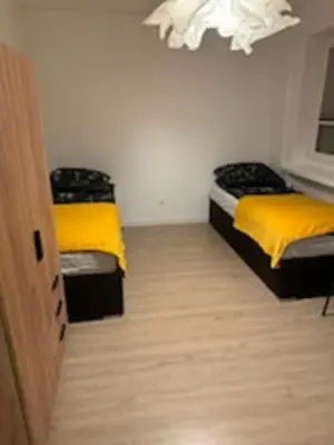two beds in a small room with yellow sheets at Podłęże, Niepołomice, noclegi, kwatery pracownicze dla firm