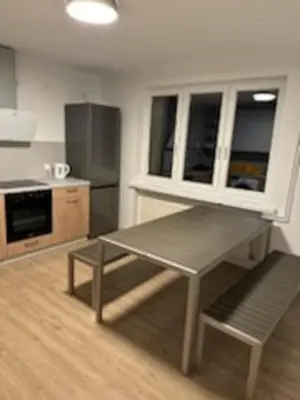 a kitchen with a table and a stainless steel refrigerator at Podłęże, Niepołomice, noclegi, kwatery pracownicze dla firm