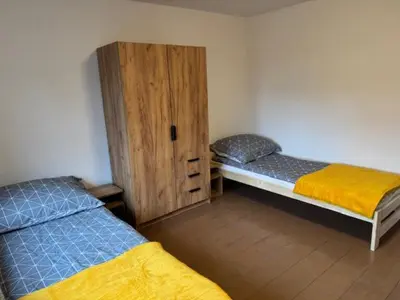 a room with two beds and a wooden cabinet at Niepołomice,noclegi, pokoje, cały dom, kwatery pracownicze in Niepołomice