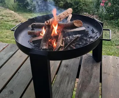 a fire in a grill on a wooden table at Dom nad Potokiem in Korzkiew