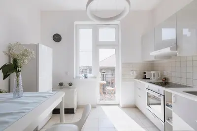 a white kitchen with a table and a window at Spacious City Centre Apartment - Słowackiego in Kraków