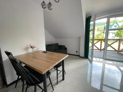 a dining room with a wooden table and chairs at Apartament Zawoja in Zawoja