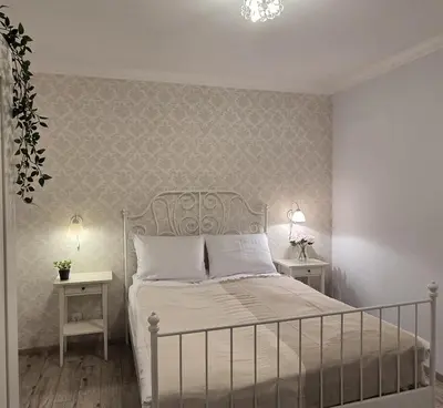 a bedroom with a white bed with two tables at Lightrooms Apartments in Kraków