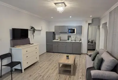 a living room with a couch and a kitchen at Lightrooms Apartments in Kraków