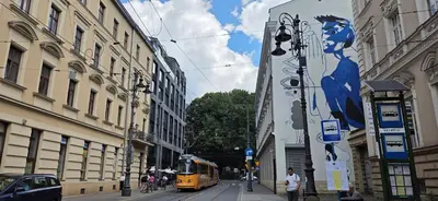 a yellow bus driving down a city street with buildings at Lightrooms Apartments in Kraków