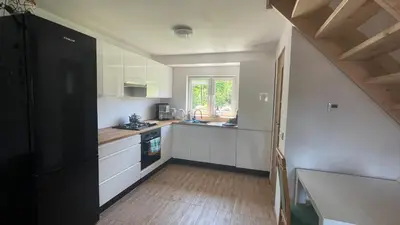 a small kitchen with white cabinets and a window at Domek w Limanowej in Limanowa