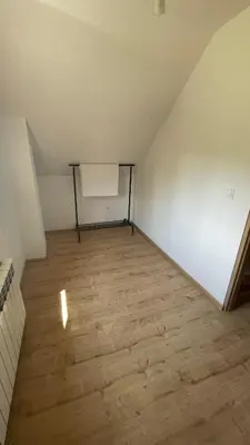 an attic room with a white wall and wooden floors at Domek w Limanowej in Limanowa