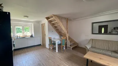 a living room with a table and a spiral staircase at Domek w Limanowej in Limanowa