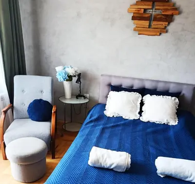 a bedroom with a blue bed and a chair at EliBlue -Twój apartament in Trzebieńczyce
