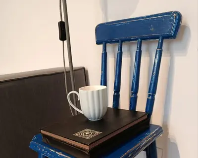 a blue chair with a cup on a book at EliBlue -Twój apartament in Trzebieńczyce
