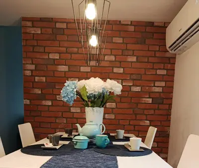 a table with a vase of flowers on a brick wall at EliBlue -Twój apartament in Trzebieńczyce