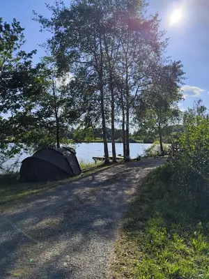 a tent on the side of a road next to a lake at Domki pod skarpą Zator 27 in Zator