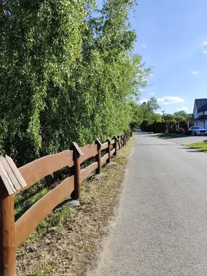 a wooden fence on the side of a road at Domki pod skarpą Zator 27 in Zator