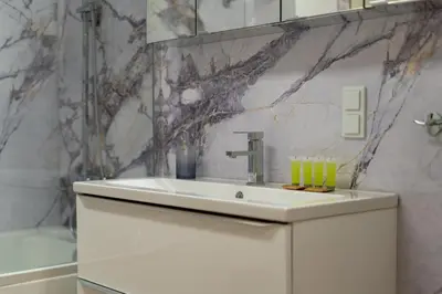 a bathroom with a white sink and a marble wall at Bohomolca Chic Studio with Garden by BookingHost in Kraków