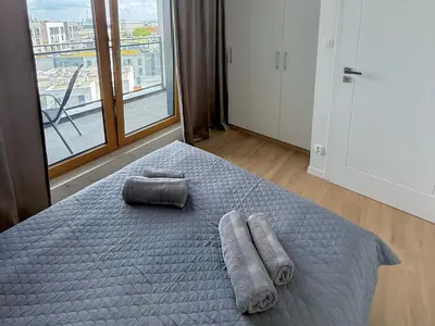 a bedroom with a bed with towels and a window at Modern Blue Apartment in Kraków